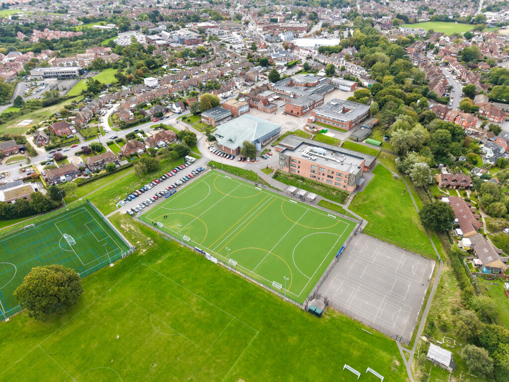 An aerial view of Hailsham Academy secondary phase site, showing the school sports fields and astro, school buildings and surrounding residential roads,